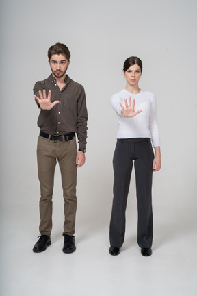 Vista frontal de una joven pareja en ropa de oficina extendiendo la mano