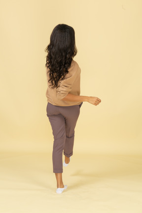 Vista posterior de una mujer joven caminando de piel oscura