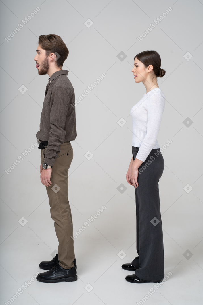 Vista lateral de um jovem casal com roupas de escritório lambendo os lábios