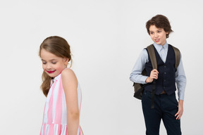 Little girl with a smeared lipstick on her face and a boy laughing at her