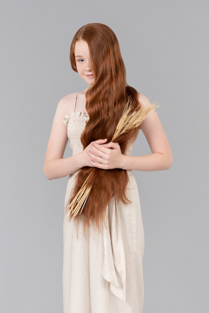 Teenage girl with red flowing hair holding wheat ears