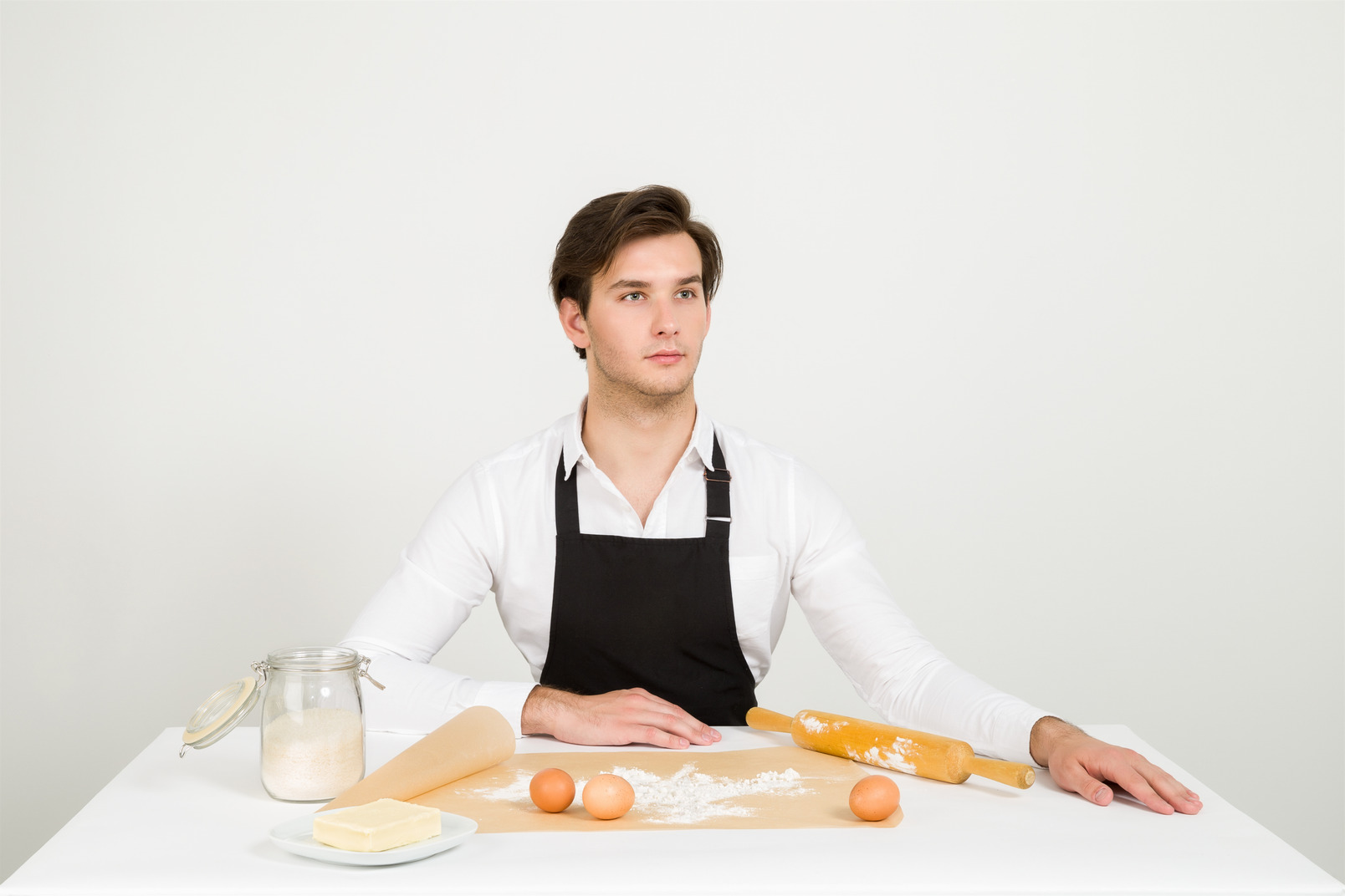 Male chef sitting at the table with ingredients and cooking tools on it