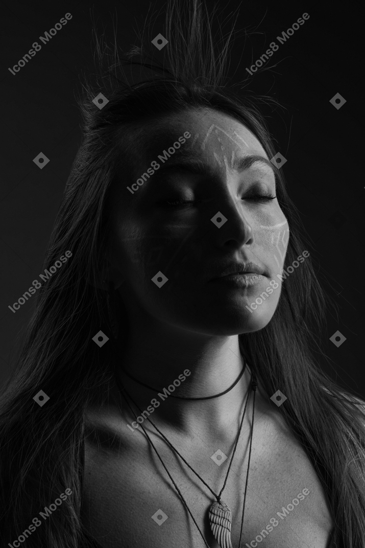 Retrato de cabeza a hombro noir de una mujer joven con arte facial y los ojos cerrados