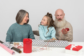 Grands-parents et petite-fille emballant des cadeaux de noël