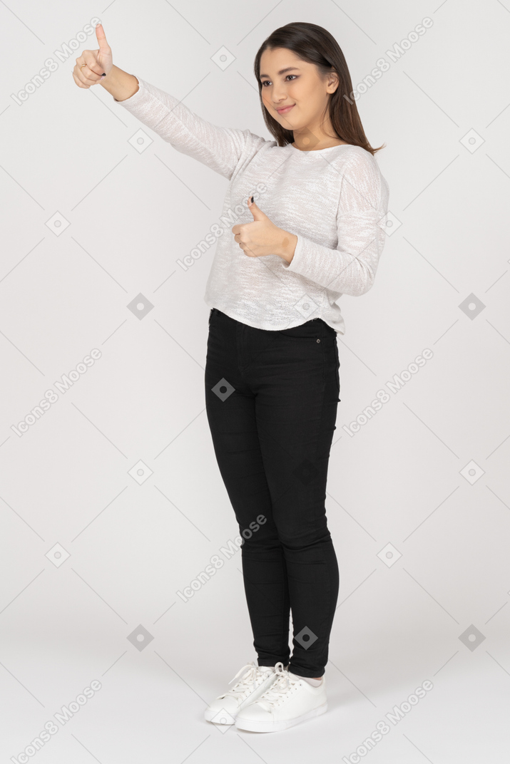 Three-quarter view of a young indian female in casual clothing showing thumbs up