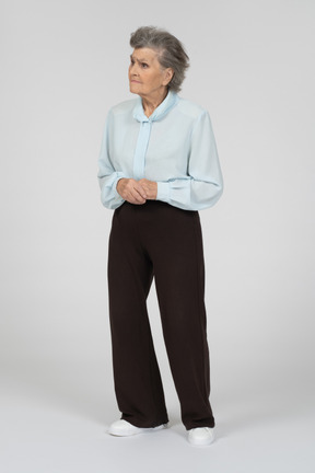 Вид спереди пожилой женщины, выглядящей грустной со сложенными руками