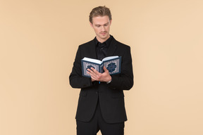 A white man in a fully black suit holding the quran