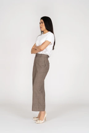 Three-quarter view of a naughty young lady in breeches and t-shirt crossing hands