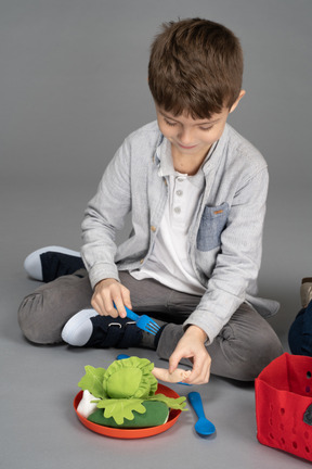 Um garotinho brincando com brinquedos de comida