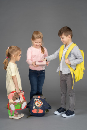 Cheerful little girl sharing toys with friends