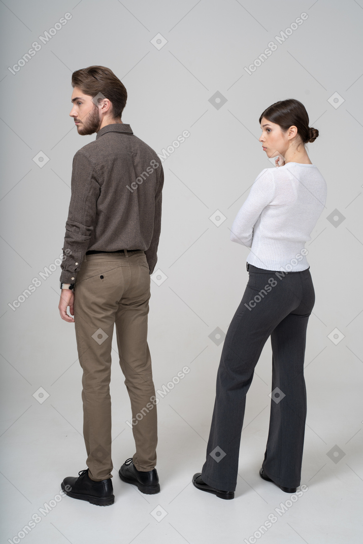 Three-quarter back view of a young couple in office clothing looking aside