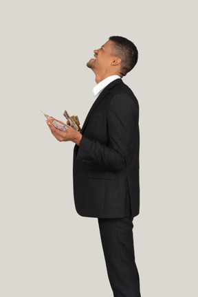 Seitenansicht eines jungen mannes im schwarzen anzug mit banknoten