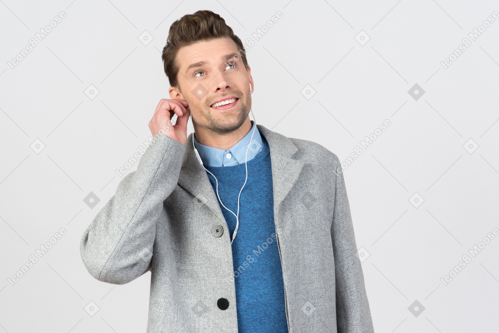 Handsome young guy adjusting earphones and looking up