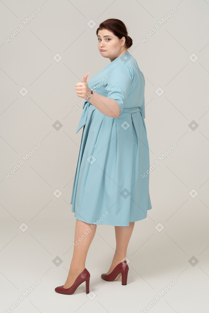 一个穿蓝色裙子的女人竖起大拇指的侧视图