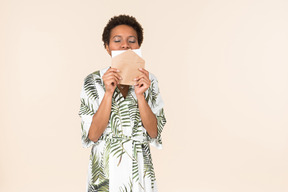 Black short-haired woman in a white and green dress, standing with an envelope in her hand