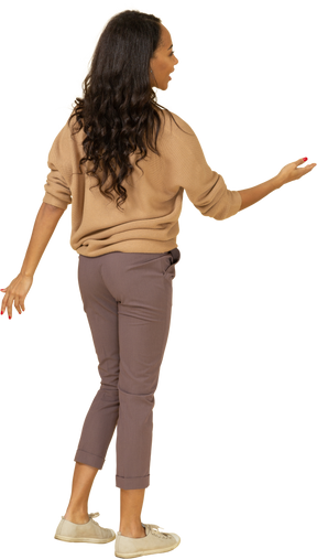 Three-quarter back view of a dark-skinned young female outstretching her hand