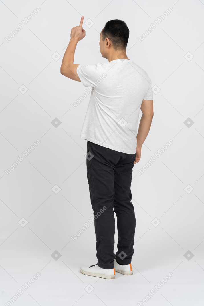 Three-quarter view of a man in casual clothes pointing up
