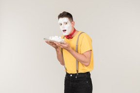 Male clown with cake cream on his face holding a cake