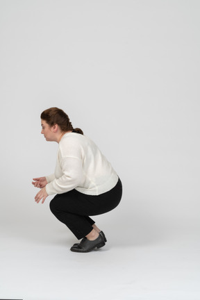 Side view of a plump woman in casual clothes squatting