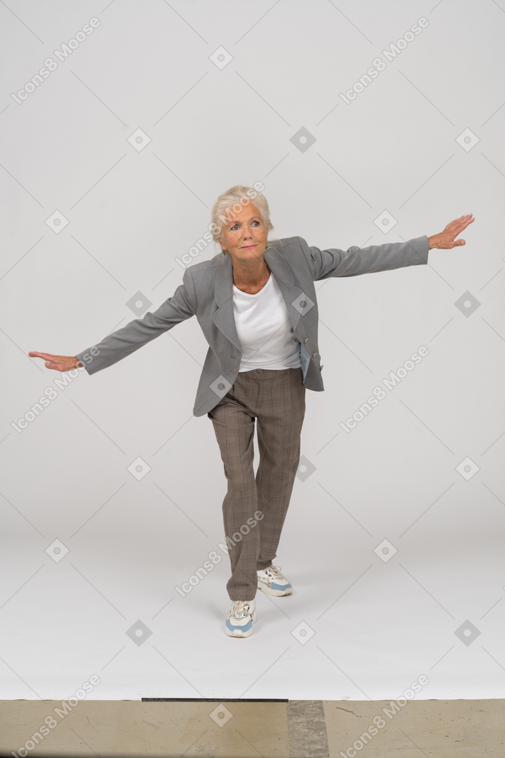 Front view of an old lady in suit standing with outspreading arms