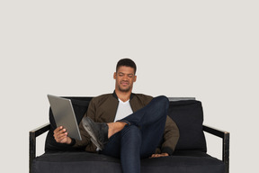 Front view of a grimacing young man sitting on a sofa