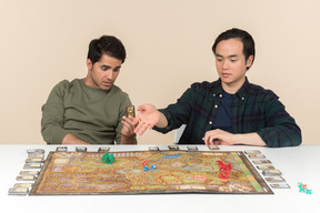 Interracial friends sitting at the table and playing board game