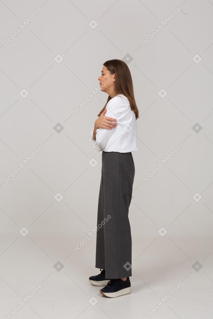 Vista lateral de una joven preocupada en ropa de oficina cruzando los brazos