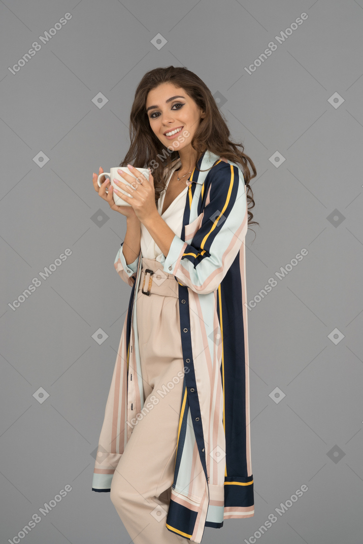 Portrait of a beautiful smiling woman holding a cup of freshly brewed coffee