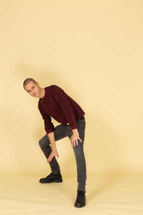 Front view of a young man in red pullover making a lunge