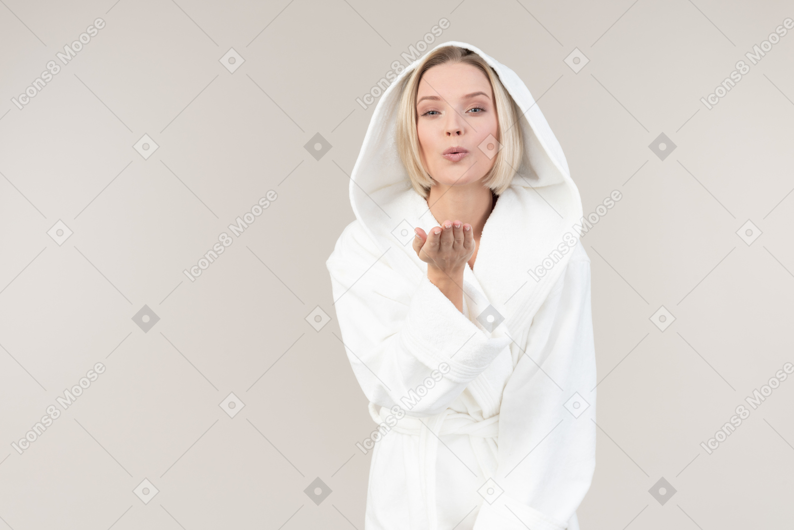 Mujer joven en bata de baño enviando besos de aire
