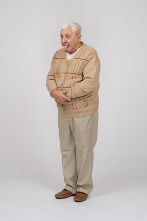 Вид спереди на старика в повседневной одежде, показывающего язык