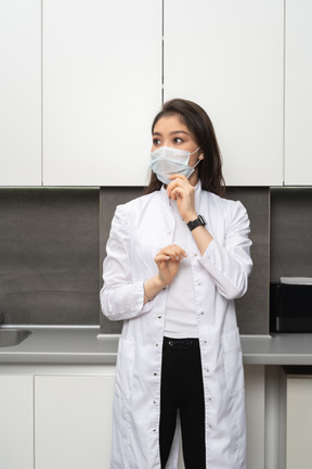 Vue de face d'une femme médecin ajustant son masque protecteur et regardant de côté