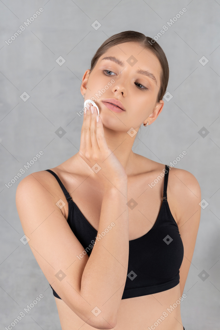 Woman removing face makeup with cotton pad