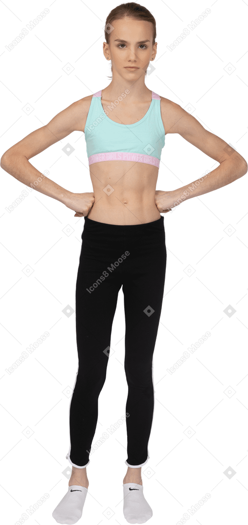 一个生气的青少年女孩，将手放在臀部上的运动服的前视图