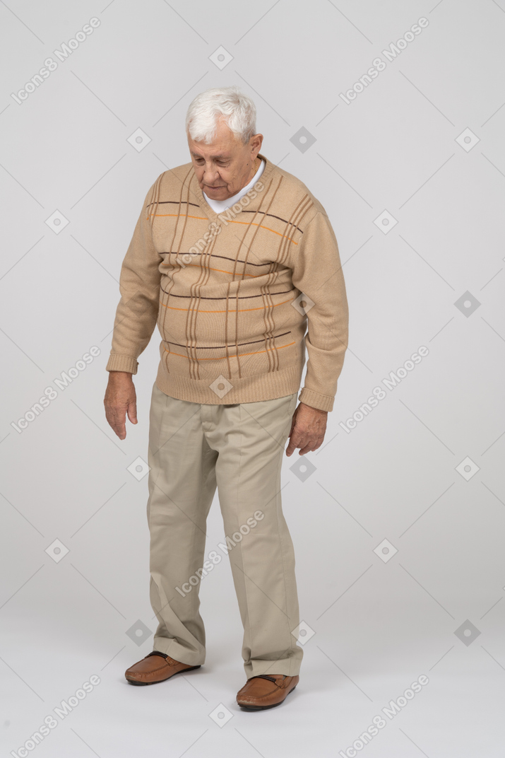 Front view of an old man in casual clothes walking forward and looking up
