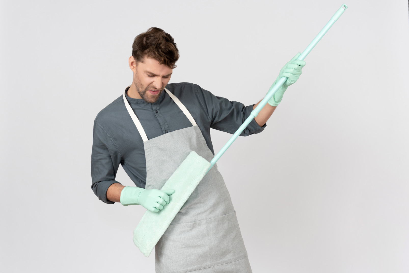 Excited househusband holding mop like a guitar