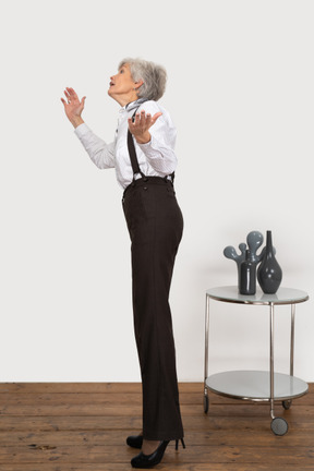 Seitenansicht einer alten dame in bürokleidung, die hände hebt, während sie nach etwas sucht