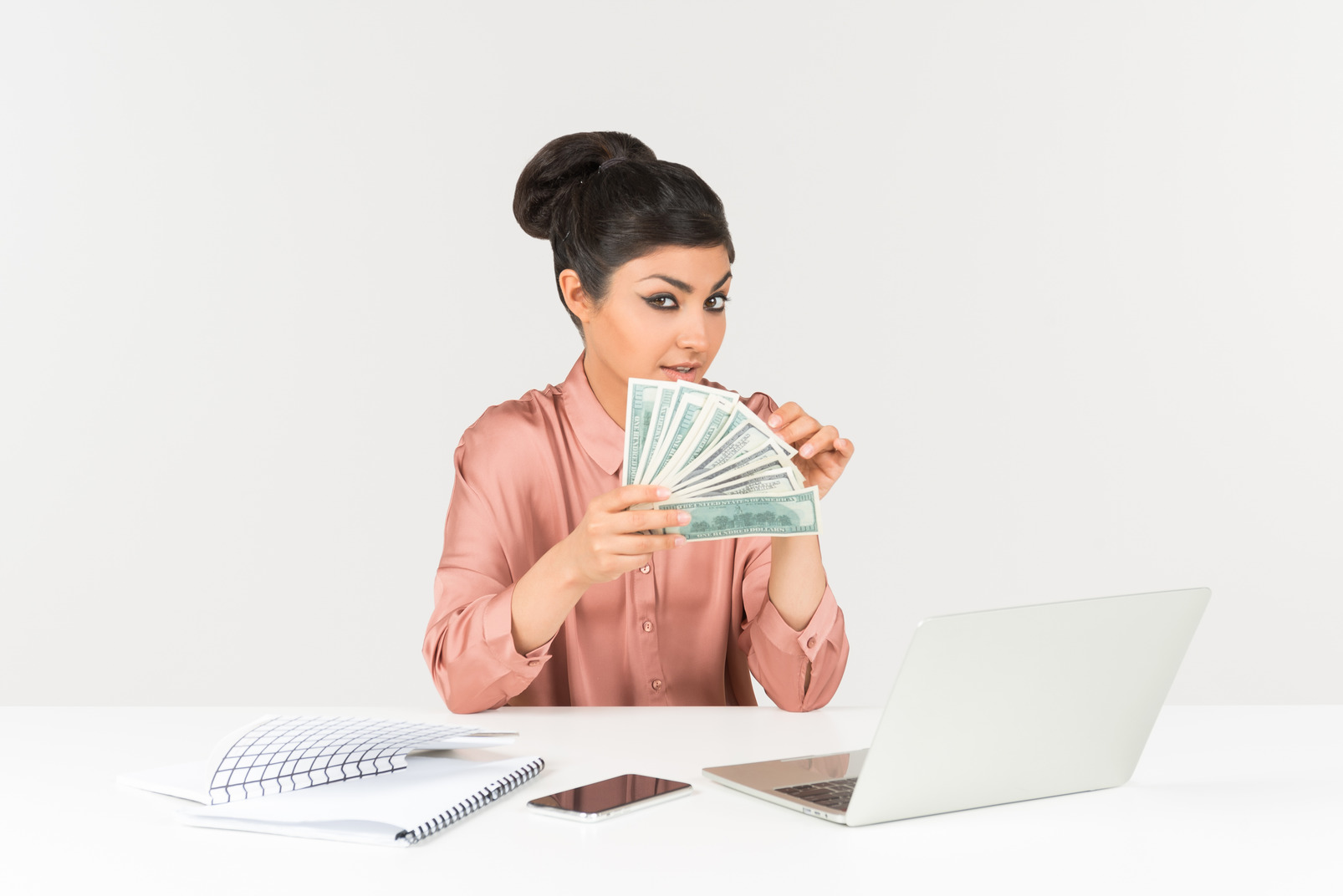 Young indian woman sitting in front of laptop and holding money bills