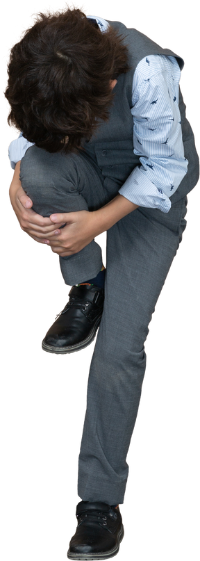 Vista frontal de um menino de terno cinza, esticando a perna