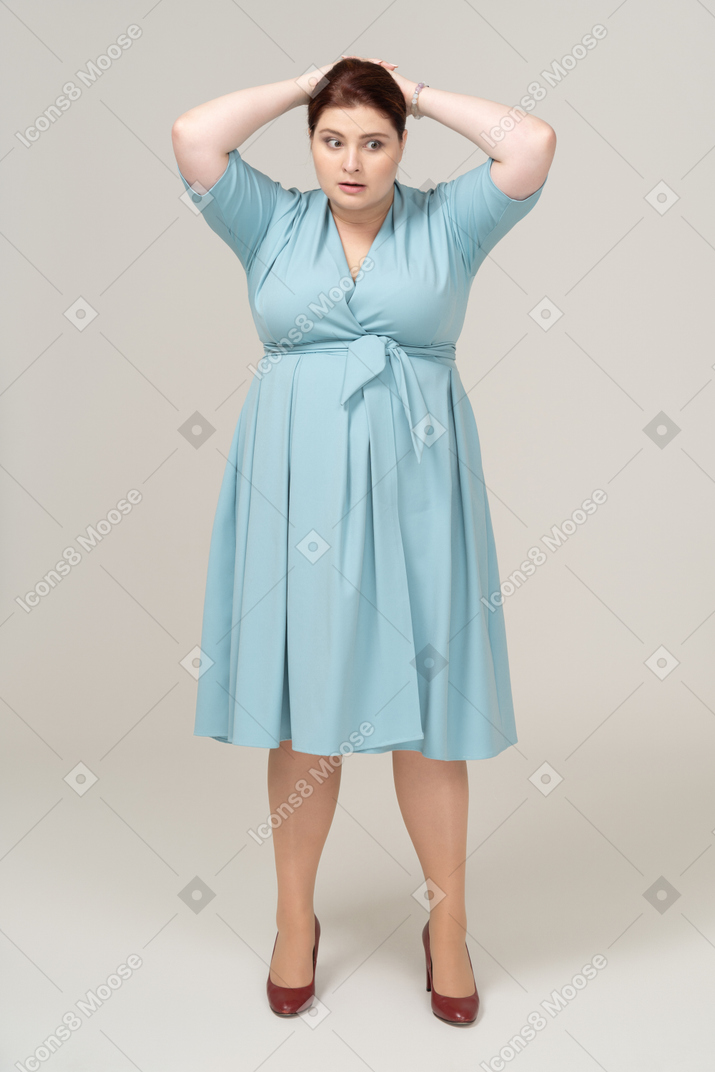 Vista frontal de uma mulher de vestido azul tocando a cabeça