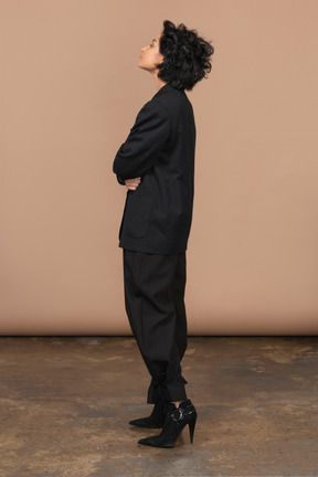 Vista lateral de uma empresária vestida de terno preto, cruzando as mãos e jogando a cabeça para trás