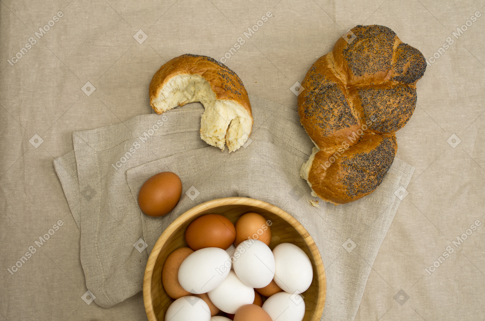 Chicken eggs and a loaf of bread on a gray tablecloth