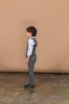 Cute boy in grey dress standing in profile