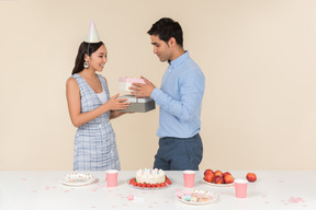 Young asian woman giving present to caucasian man