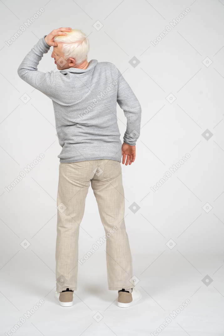 Back view of a man holding his hand on his head