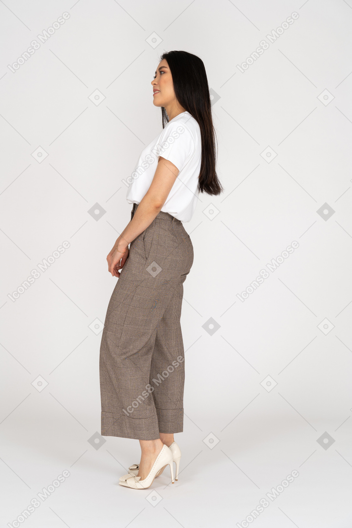 Side view of a confused young lady in breeches and t-shirt holding hands together