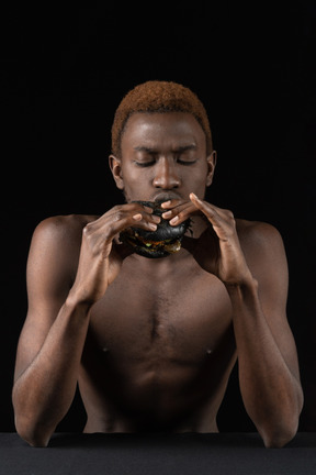 Front view of a young afro man eating a burger