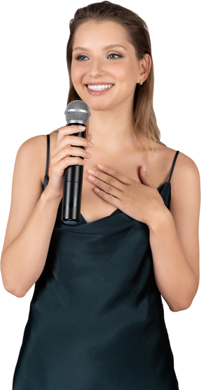Front view of a smiling young woman in night gown holding a microphone