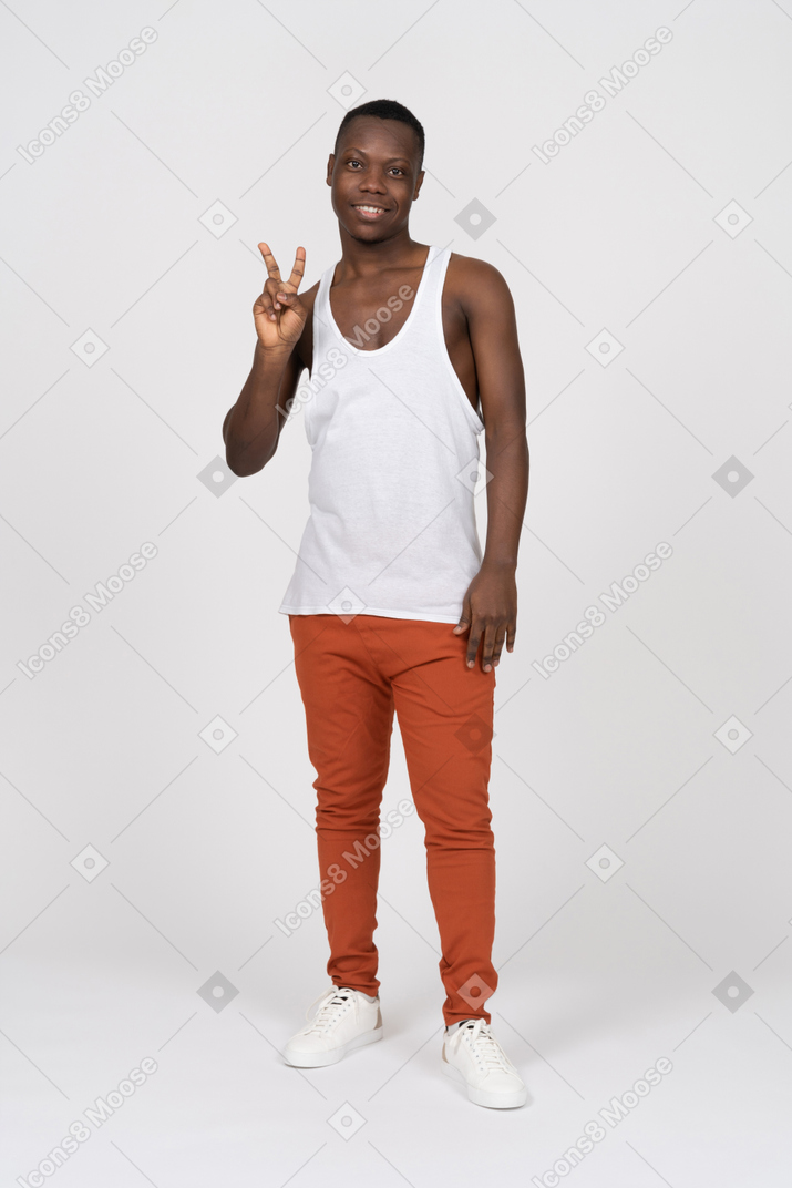 Front view of cheerful young man showing peace sign