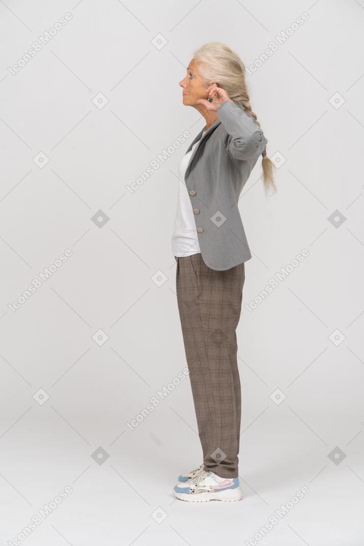 Side view of an old lady in suit posing with hands behind head